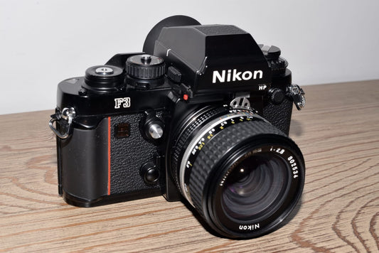 Nikon F3HP mit Nikkor 28 mm f/2,8 auf einem Holztisch