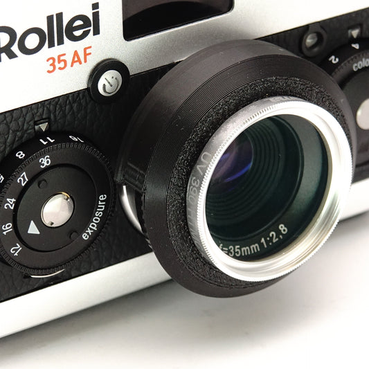 Schwarze Gegenlichtblende und silberner Filteradapter an der Analgkamera Rollei 35 AF