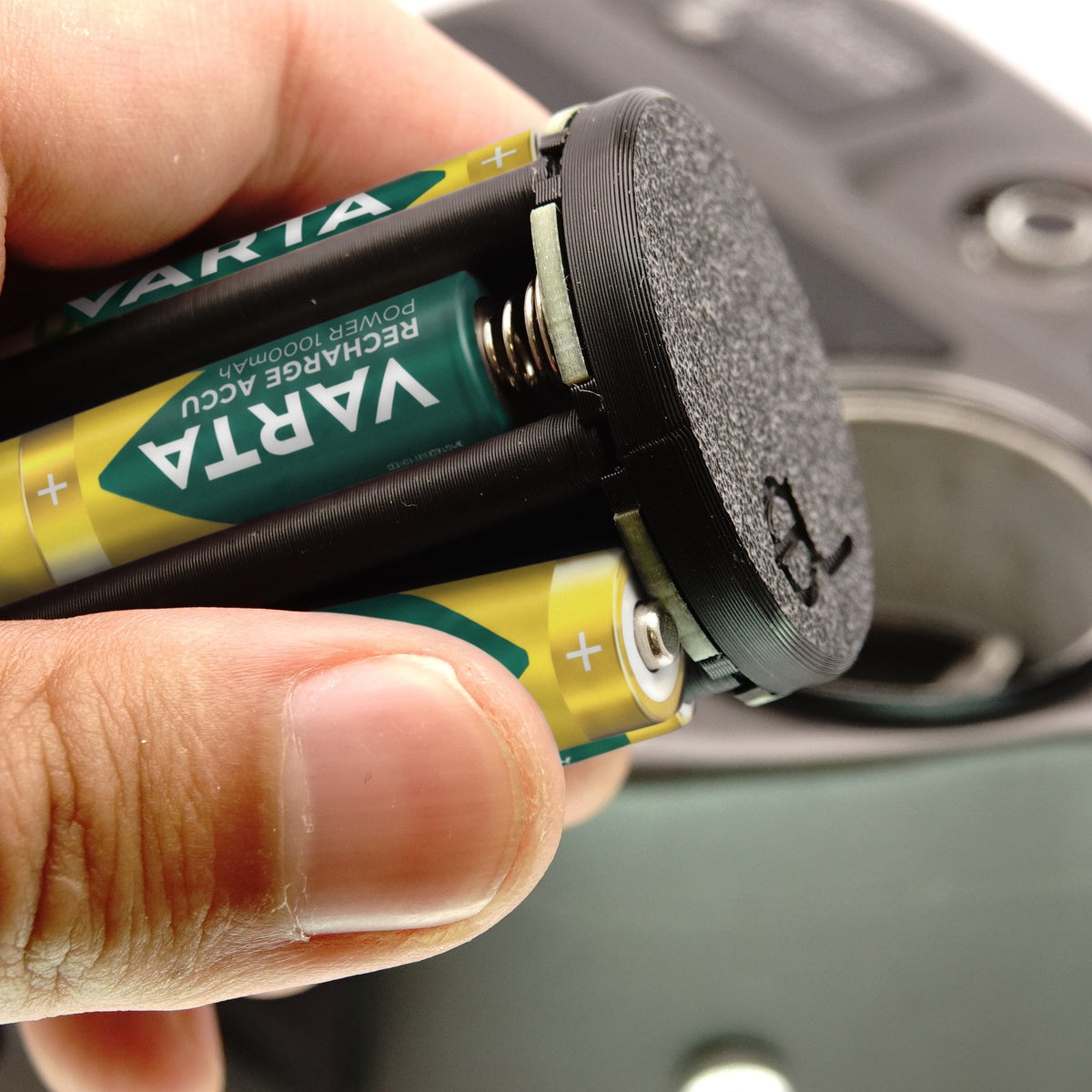 Hand hält den bestückten Batterieadapter vor eine Beaulieu Super-8-Kamera