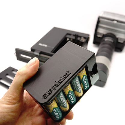 Hand hält bestückten Batterieadapter mit vier Akkus vor einem Metz Stabblitz