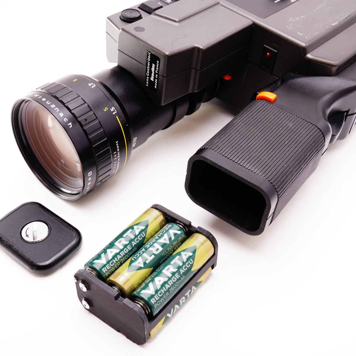 Bestückter Batterieadapter mit eingelegten Akkus neben einer Beaulieu 6008 Schmalfilmkamera