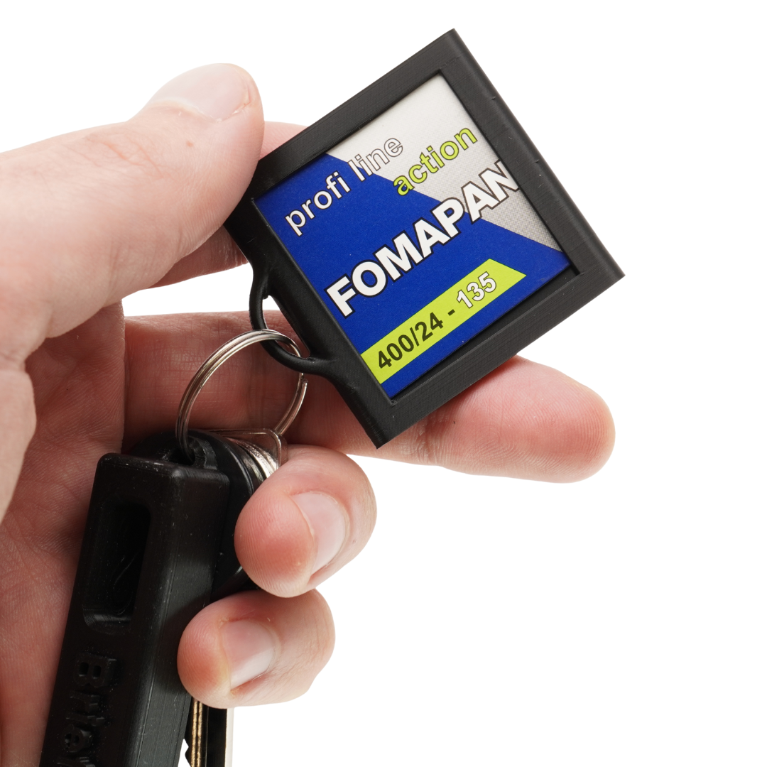 Hand hält den Halter mit eingelegter Fomapan-Filmlasche am Schlüsselbund