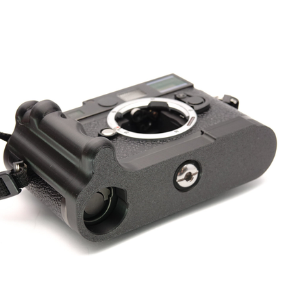 Schwarzer Handgriff an der Unterseite einer Leica Kamera mit integriertem Fach für den Akku