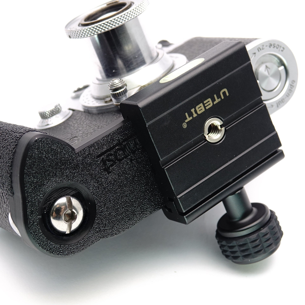 Schwarzer Handgriff mit montierter Schnellwechselplatte an der Unterseite einer analogen Leica Kamera