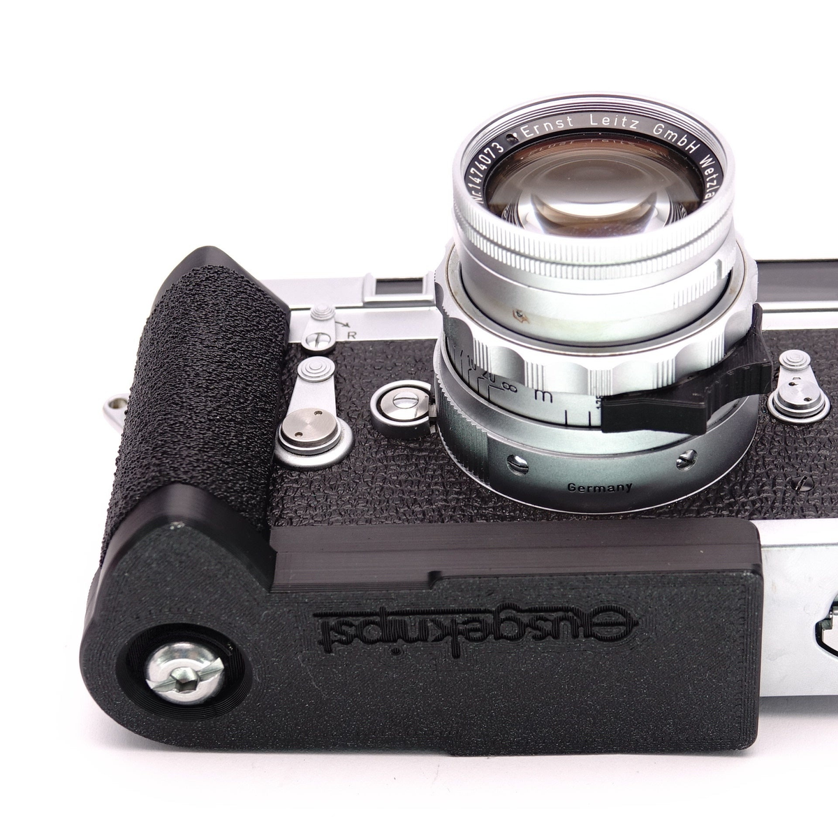 Schwarzer Handgriff mit integrierter Arca Swiss Platte an einer analogen Leica Kamera