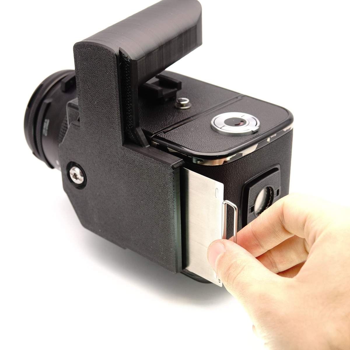 Schwarze Blitzschiene an einer Hasselblad mit montiertem Griff, während eine Hand den Magazinschieber zieht